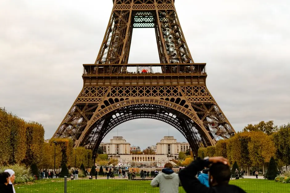 Pied de la Tour Eiffel vu à travers son arche, entouré d'arbres d'automne