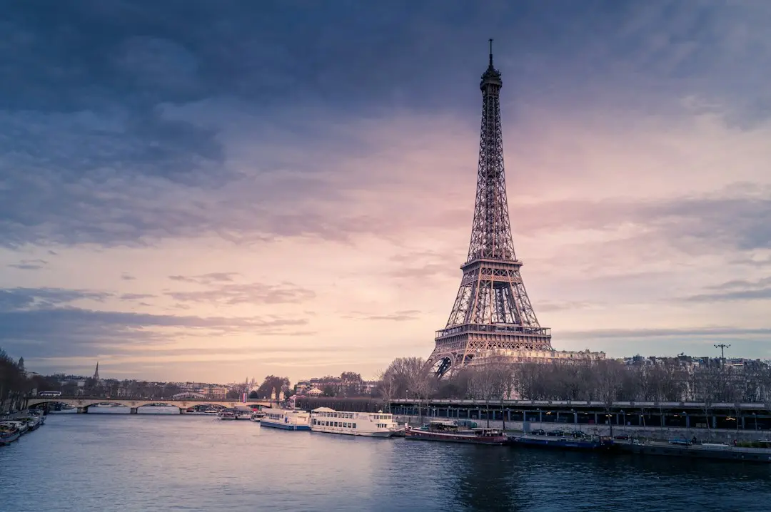 Tour Eiffel au crépuscule vue depuis la Seine, avec des bateaux sur le fleuve
