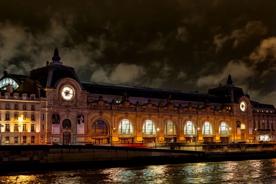 Musée d'Orsay illuminé la nuit, reflété dans la Seine