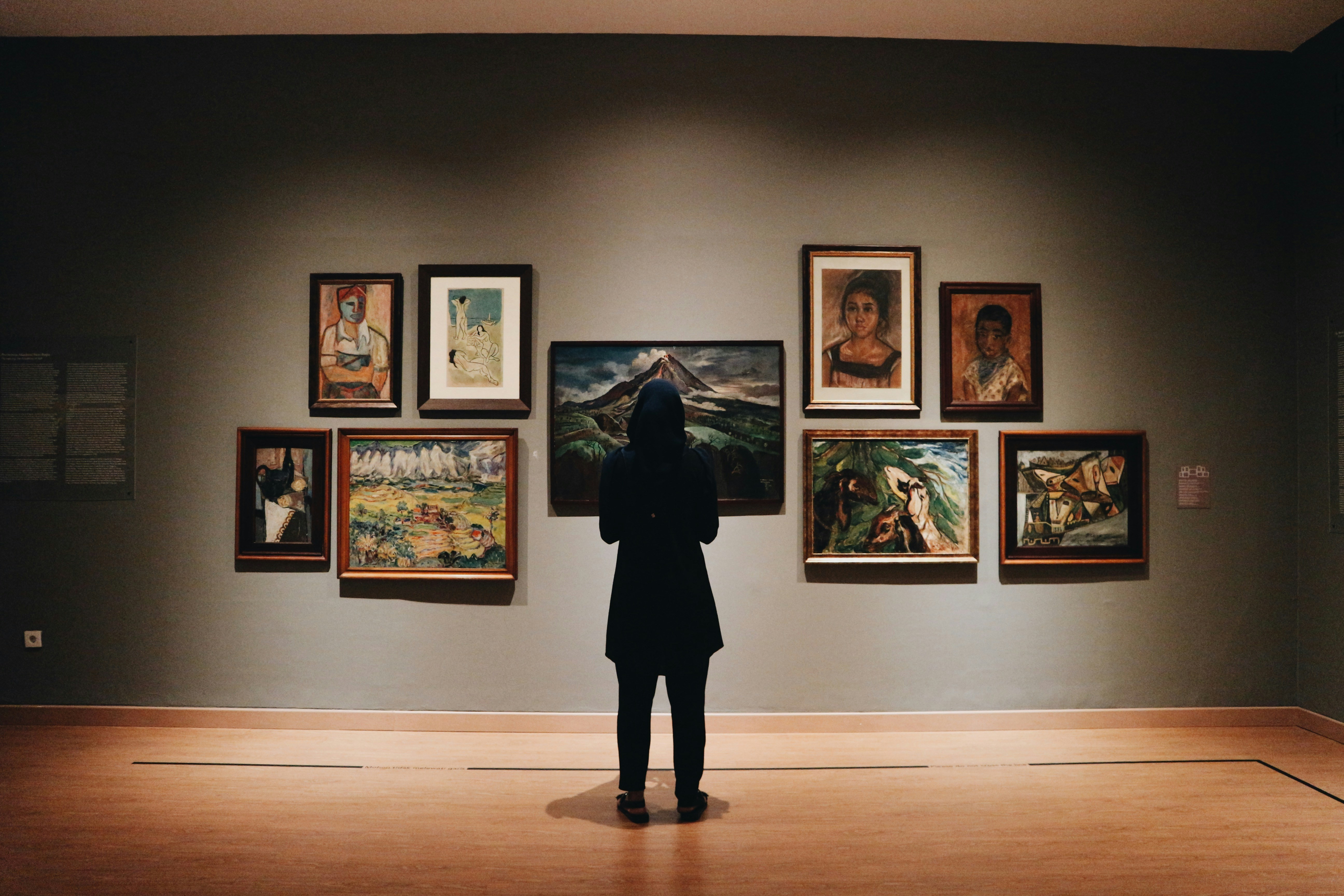 Visiteuse observant des œuvres graphiques encadrées dans une galerie d’exposition