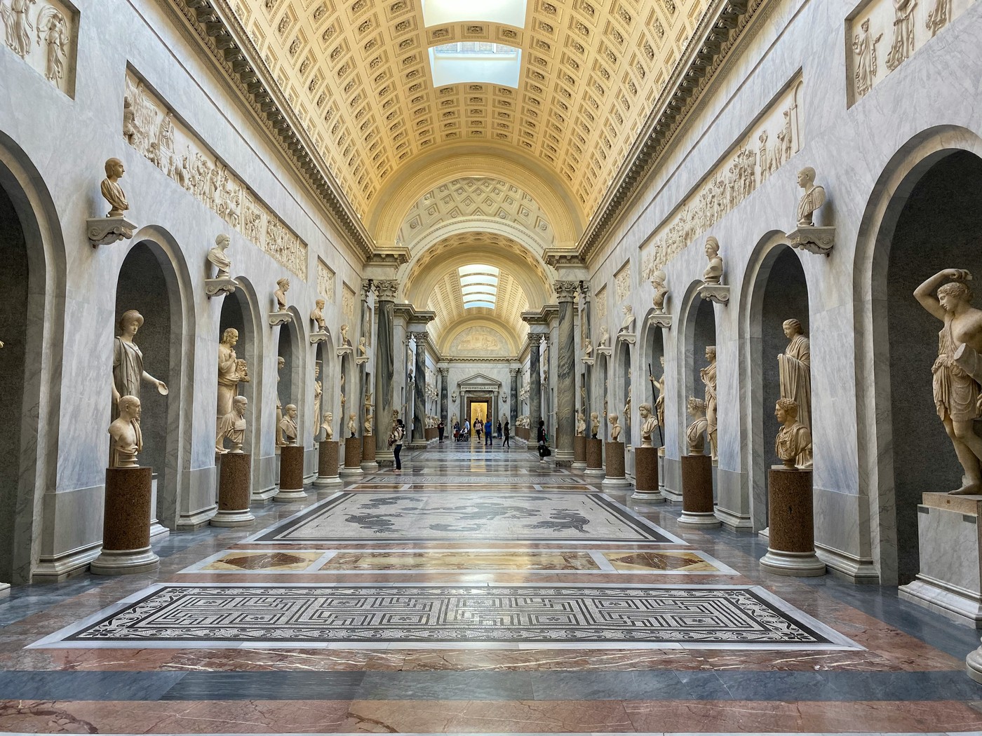 Galerie bordée de sculptures antiques et bustes en marbre aux Musées du Vatican